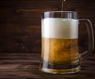 Light,Beer,Is,Poured,Into,A,Mug,On,A,Wooden