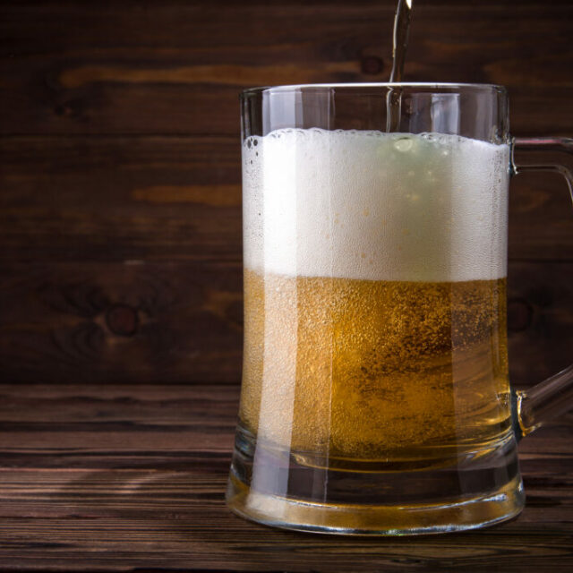 Light,Beer,Is,Poured,Into,A,Mug,On,A,Wooden